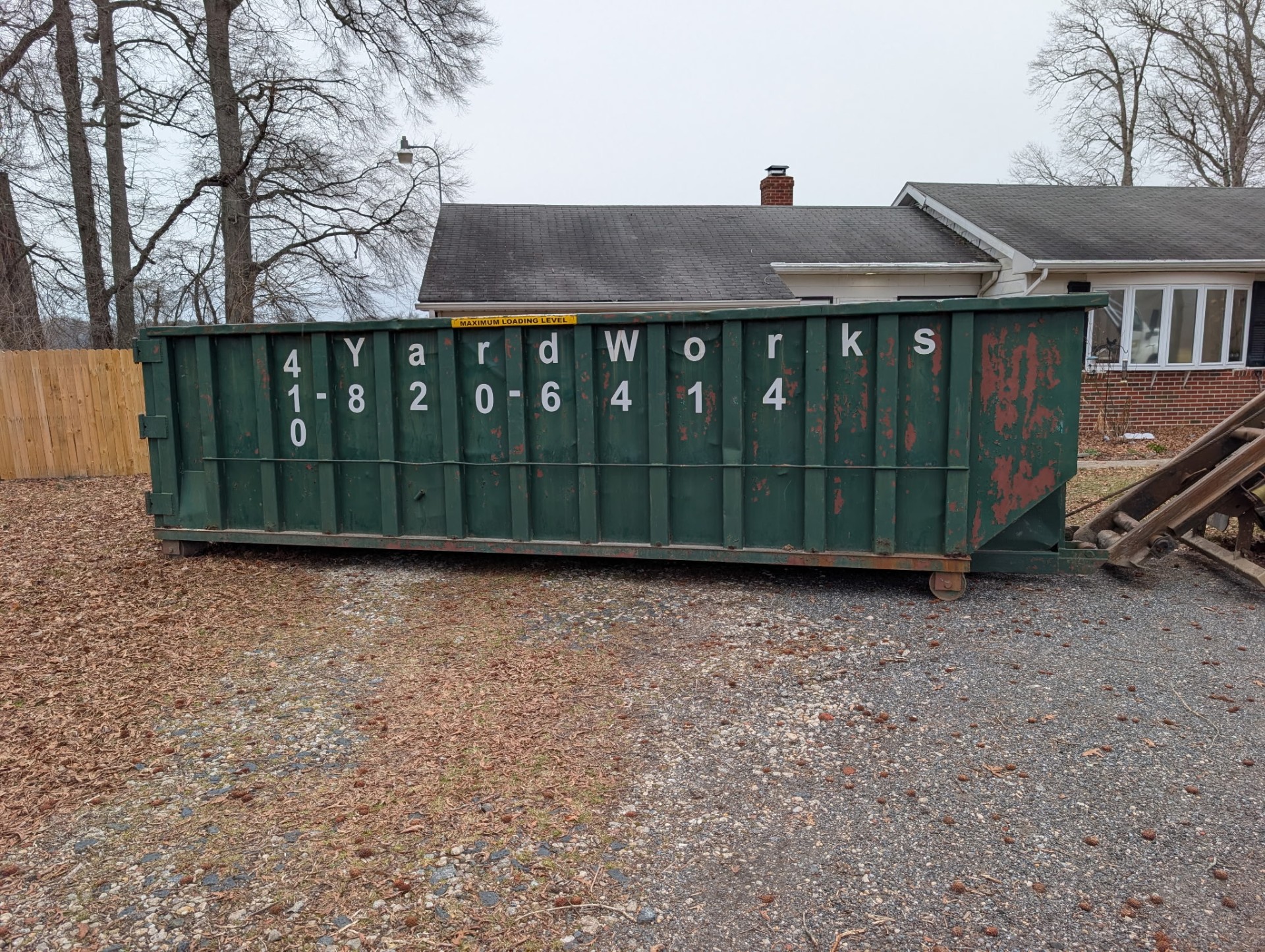 Yard Works Plus green roll-off dumpster at a residential property on the Eastern Shore